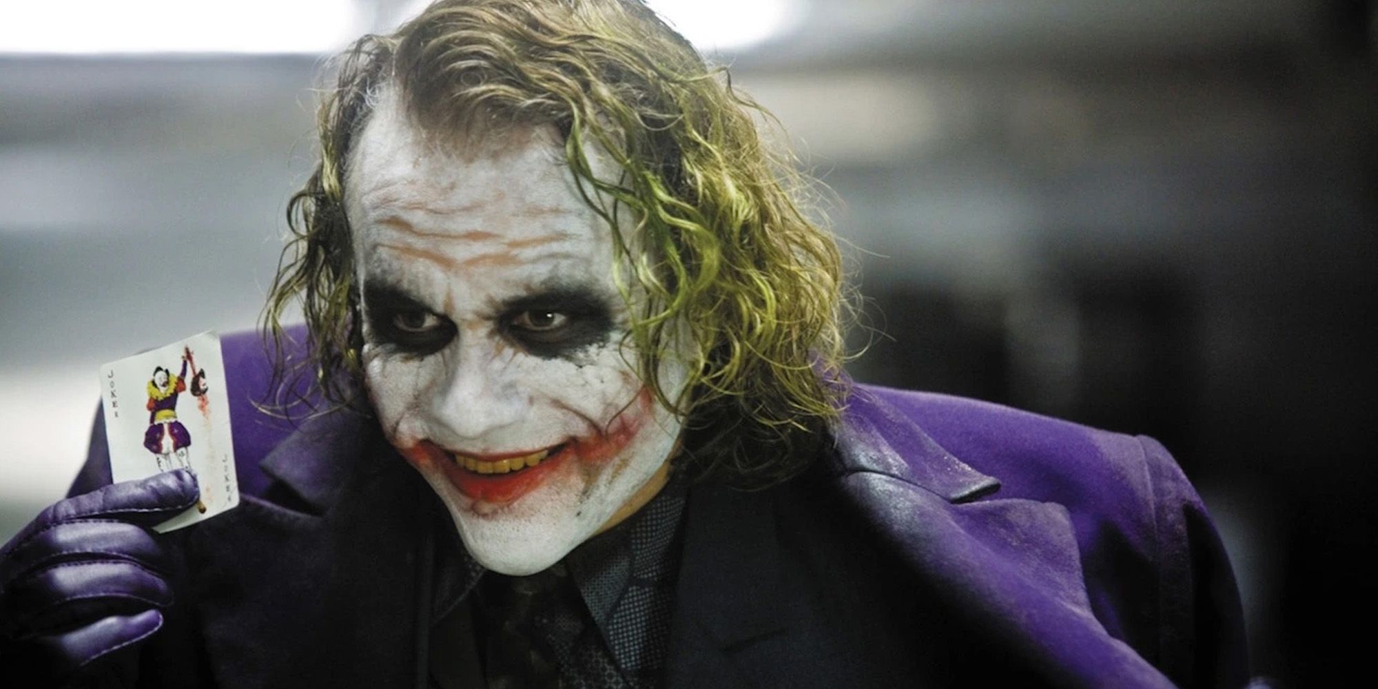 The Joker showing a Joker card and smiling in The Dark Knight