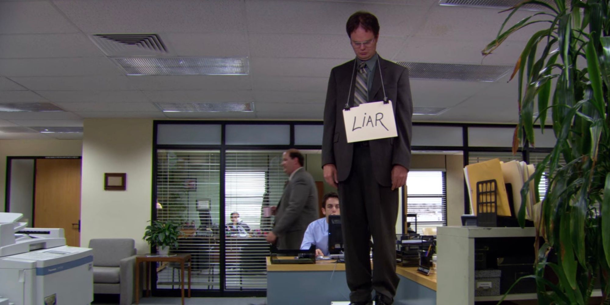 Dwight se tient debout sur son bureau avec un 