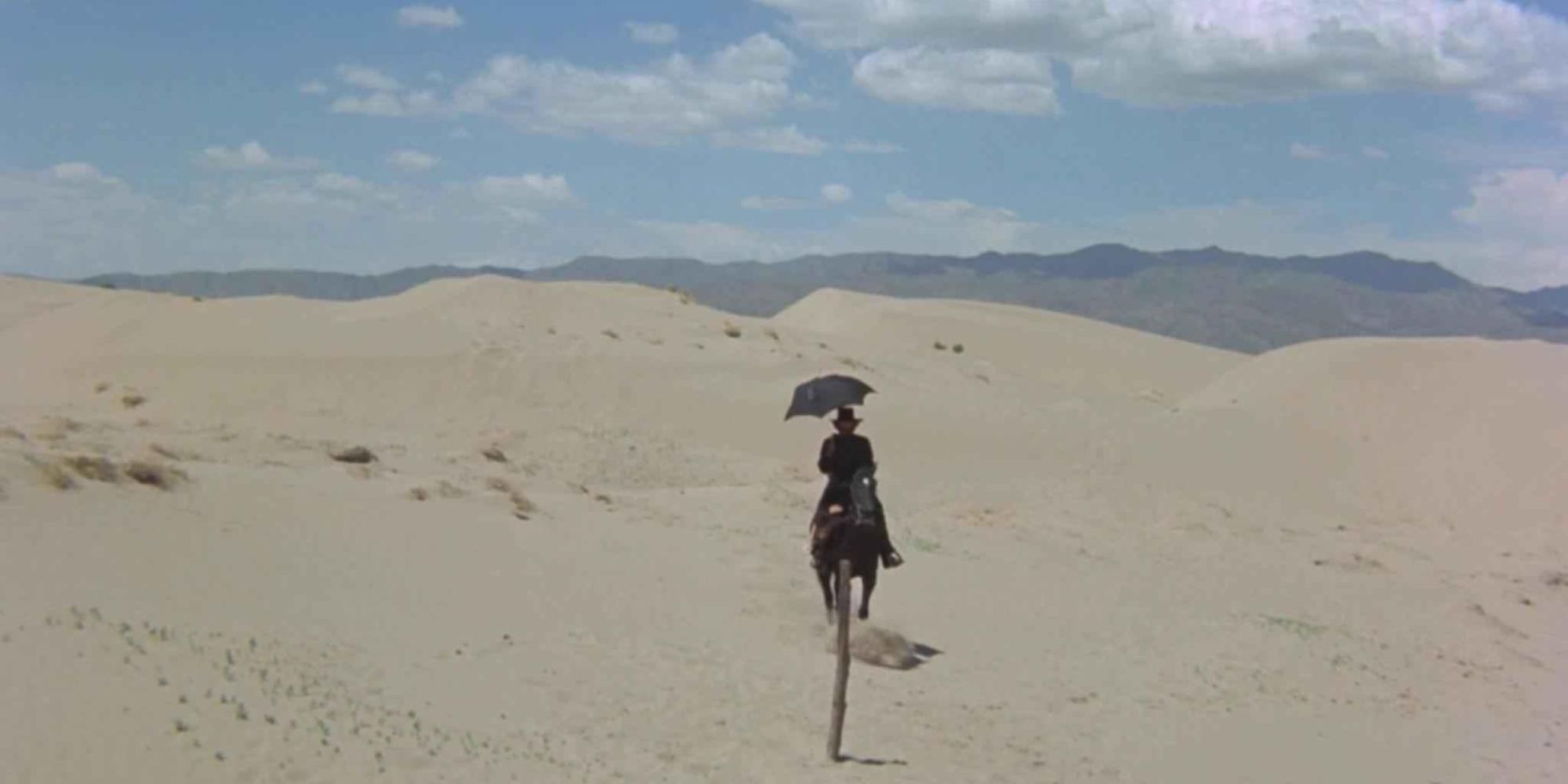A man riding on horseback through the desert in El Topo (1970)