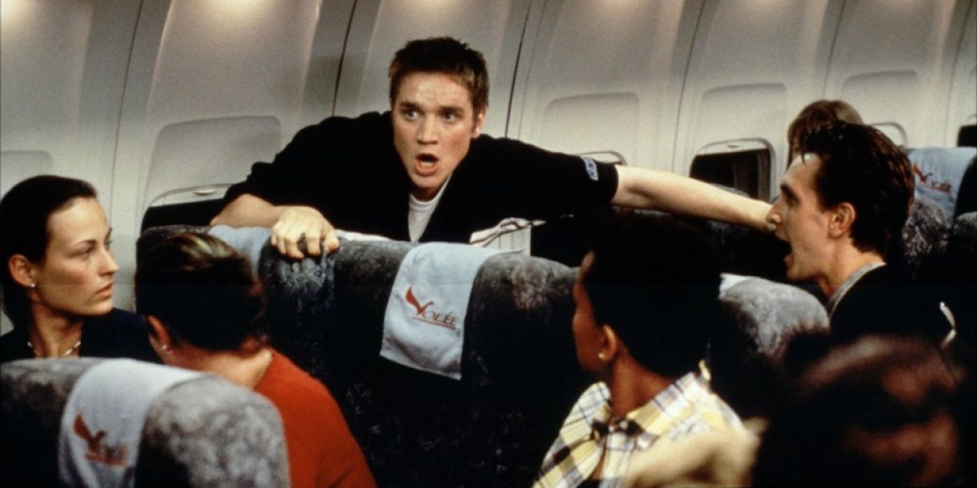 A frightened Alex gets up from his seat on the plane as others look on at Final Destination