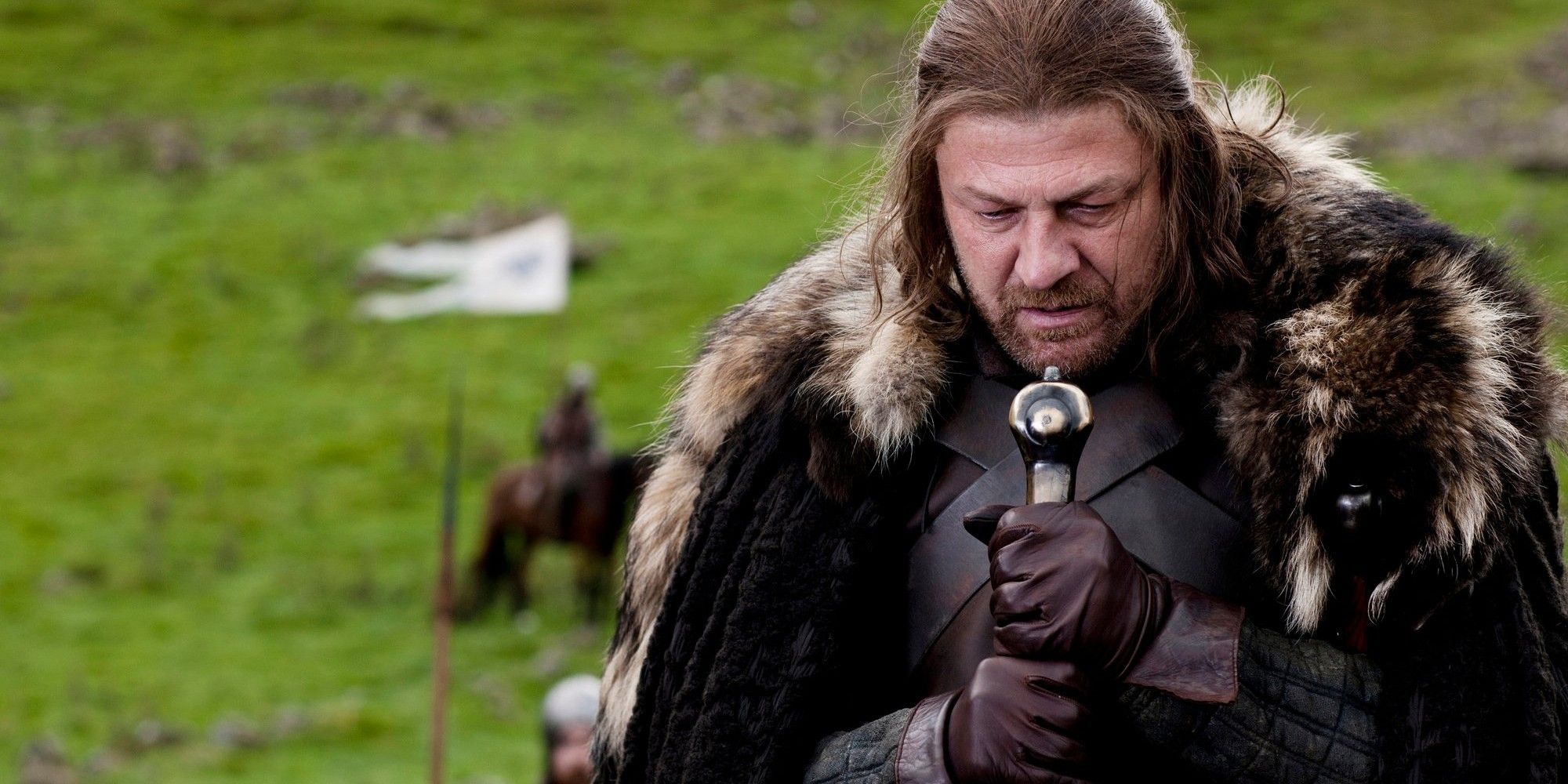 Ned Stark holding a large sword while looking down in Game of Thrones