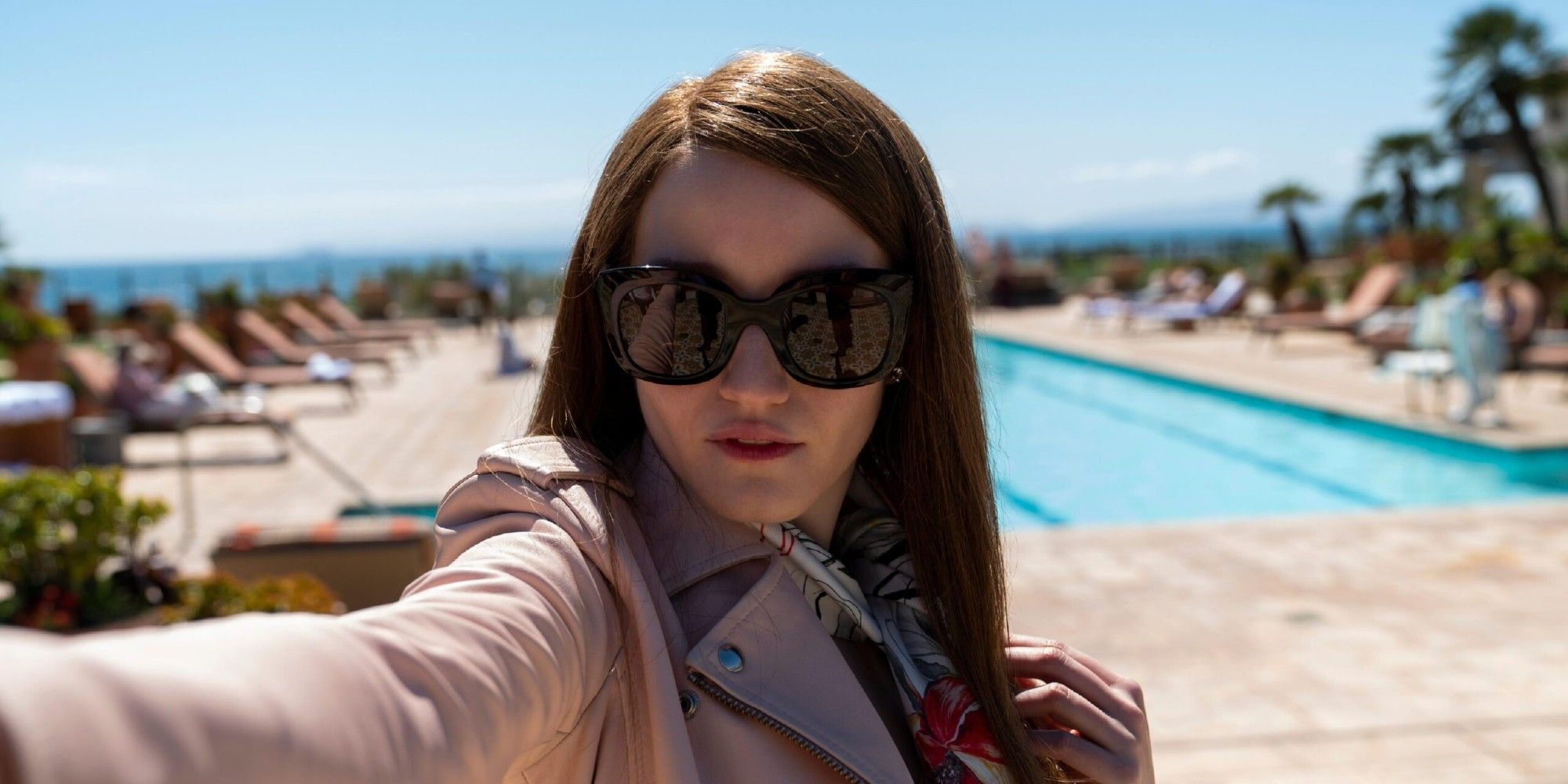 Julia Garner as Anna Delvey takes a selfie beside a pool