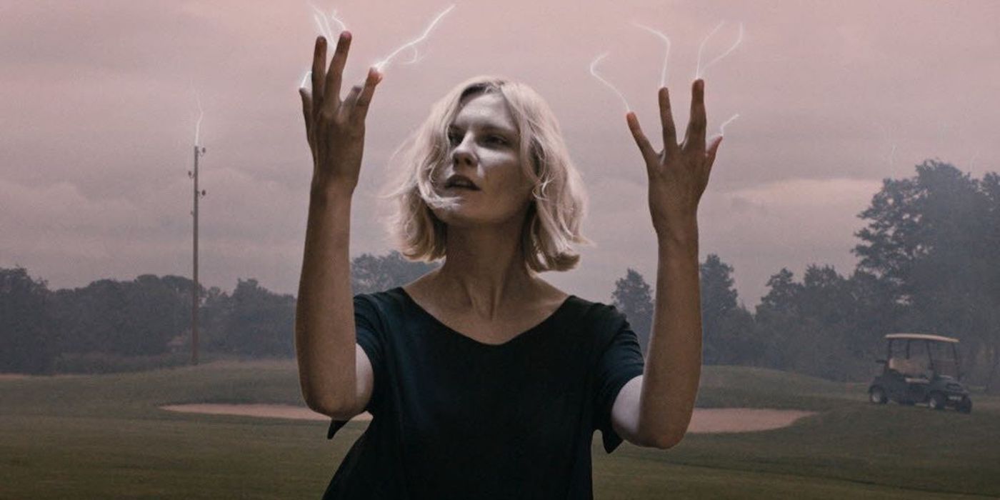 Justine looking at her hands as white energy comes from the tips of her fingers in the film Melancholia.