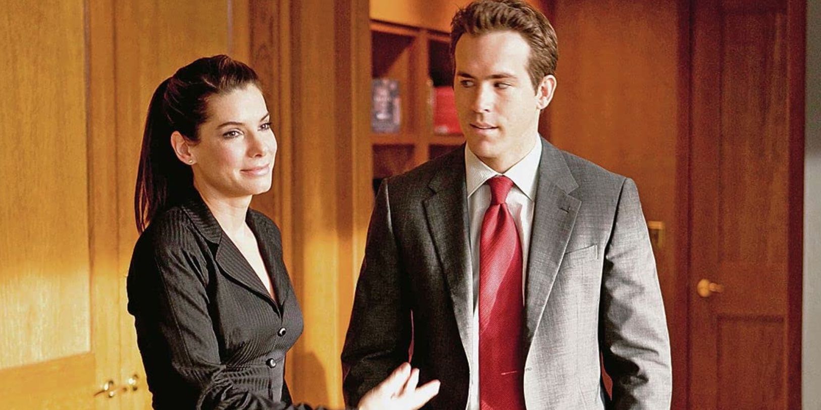Sandra Bullock and Ryan Reynolds standing in an office in 'The Proposal'