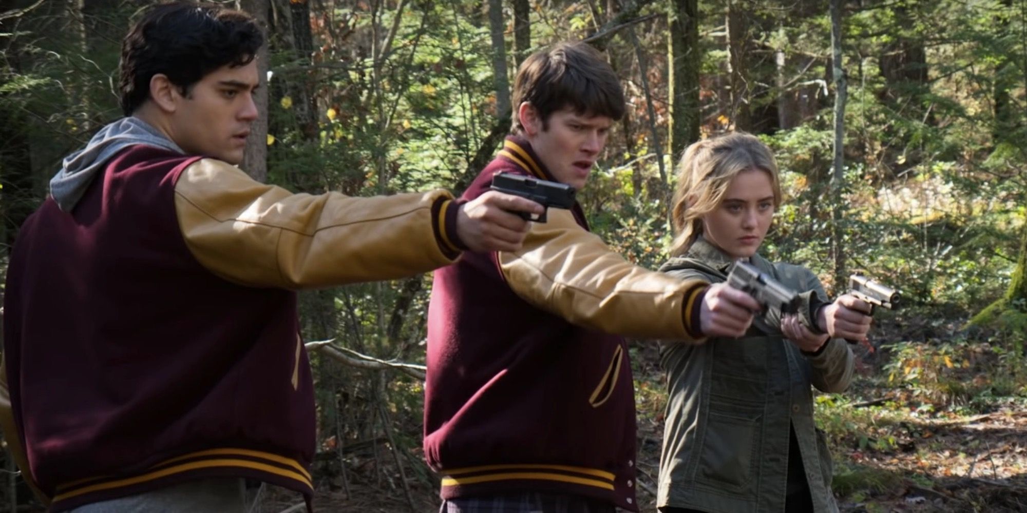 Three teenagers at the woods pointing guns at something off-camera in The Society