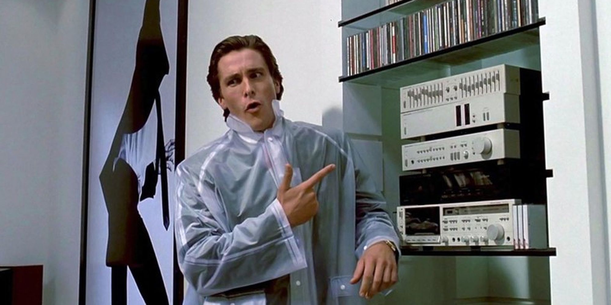 Christrian Bale as Patrick Bateman wearing a clear poncho and gesturing at a stereo in American Psycho