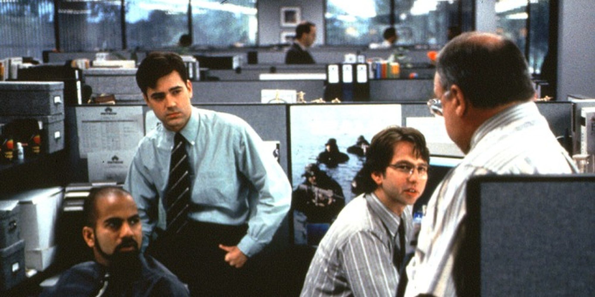 Peter and two co-workers looking at a third man with his back to the camera in Office Space