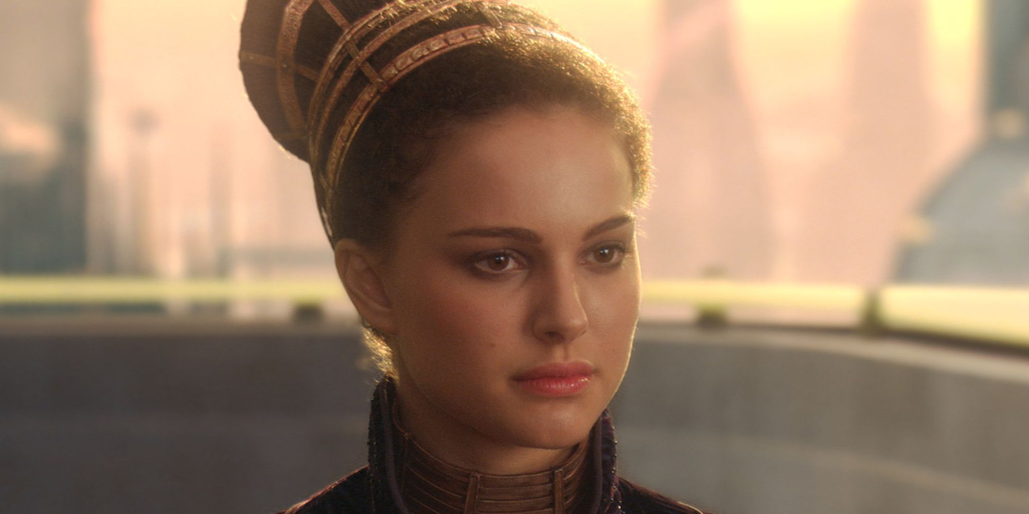 Natalie Portman as Padmé Amidala looks seriously at someone off camera, standing on a balcony in Star Wars.