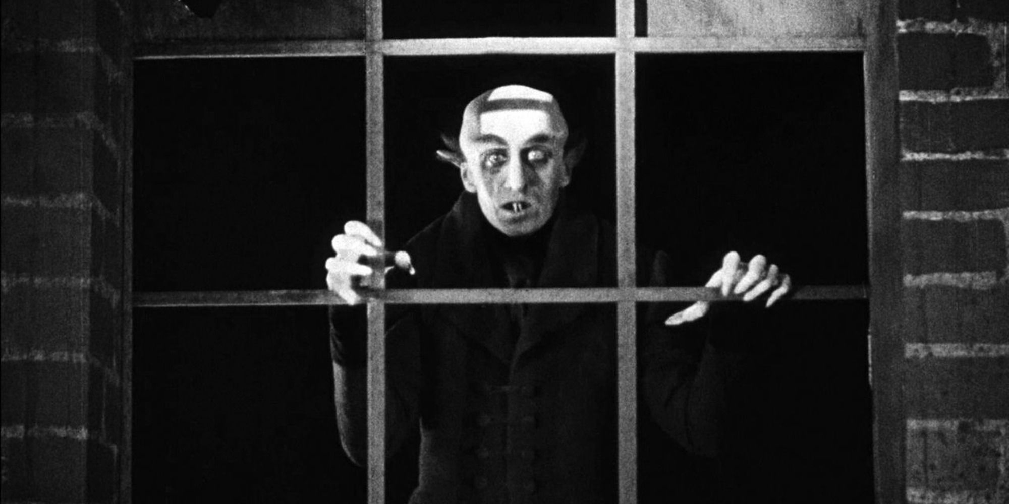 Count Orlok, played by Max Schreck, looking outside a window in Nosferatu