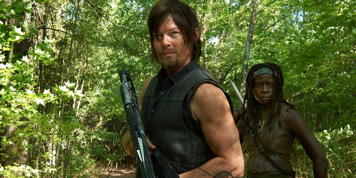 Norman Reedus as Daryl Dixon and Danai Gurira as Michonne standing in a forest with weapons