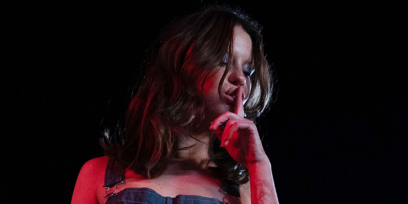 Mia Goth does a "shush" motion while being lit by a dull red light in 'X.'