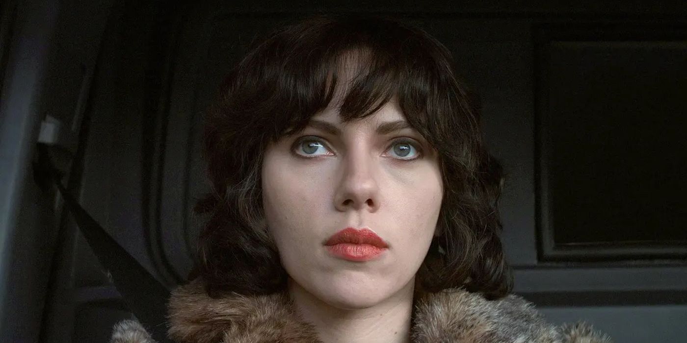 Laura (Scarlett Johansson) sits and watches from the front seat of a vehicle. 