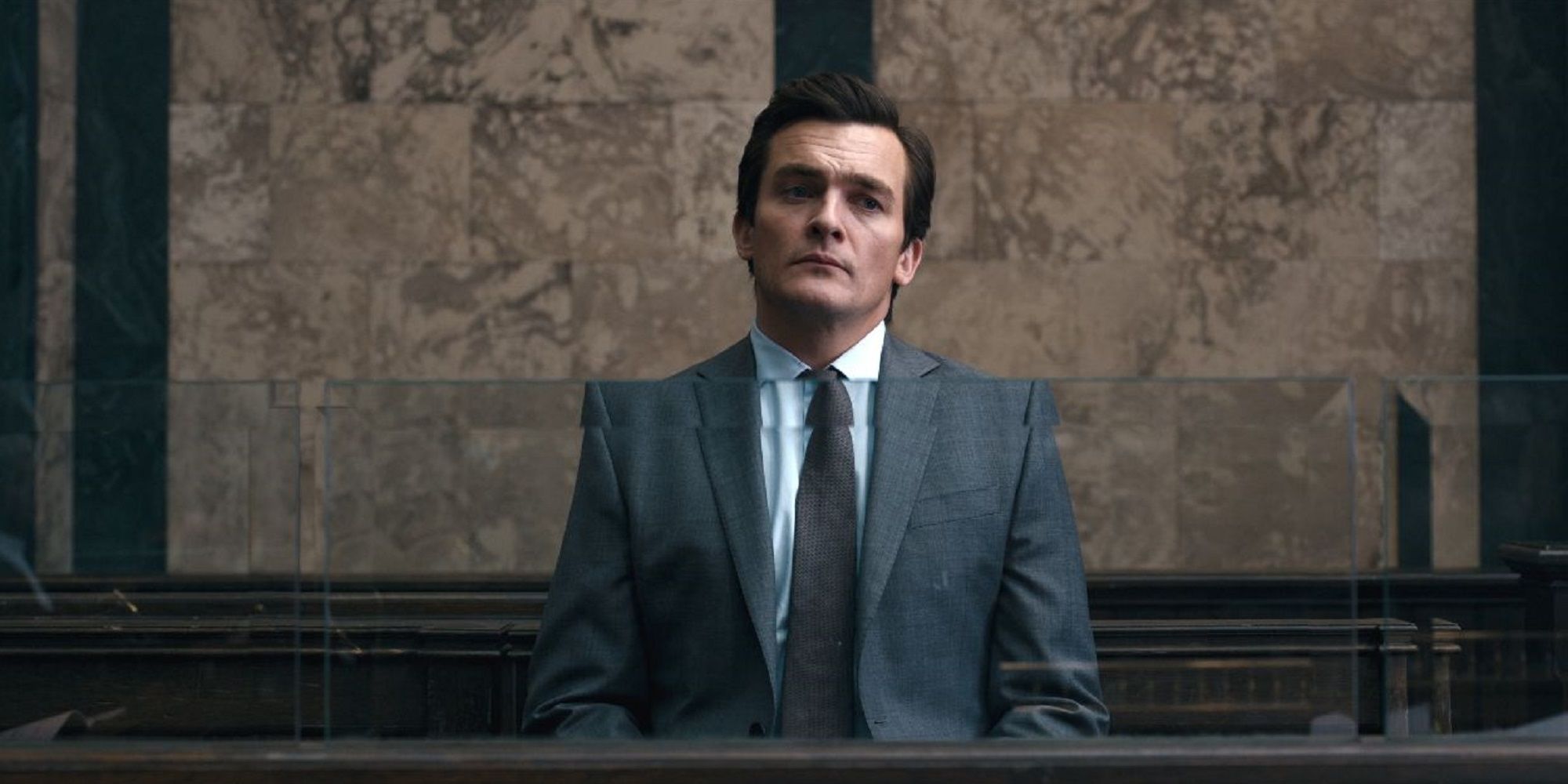 Rupert Friend wearing a suit in a court room in Anatomy of a Scandal