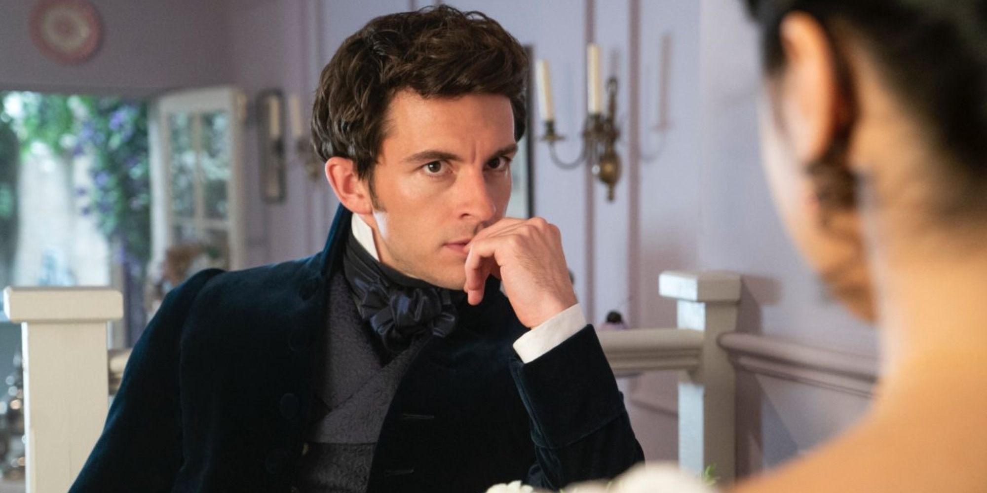 Jonathan Bailey dans le rôle d'Anthony Bridgerton regardant une jeune femme de l'autre côté de la table 