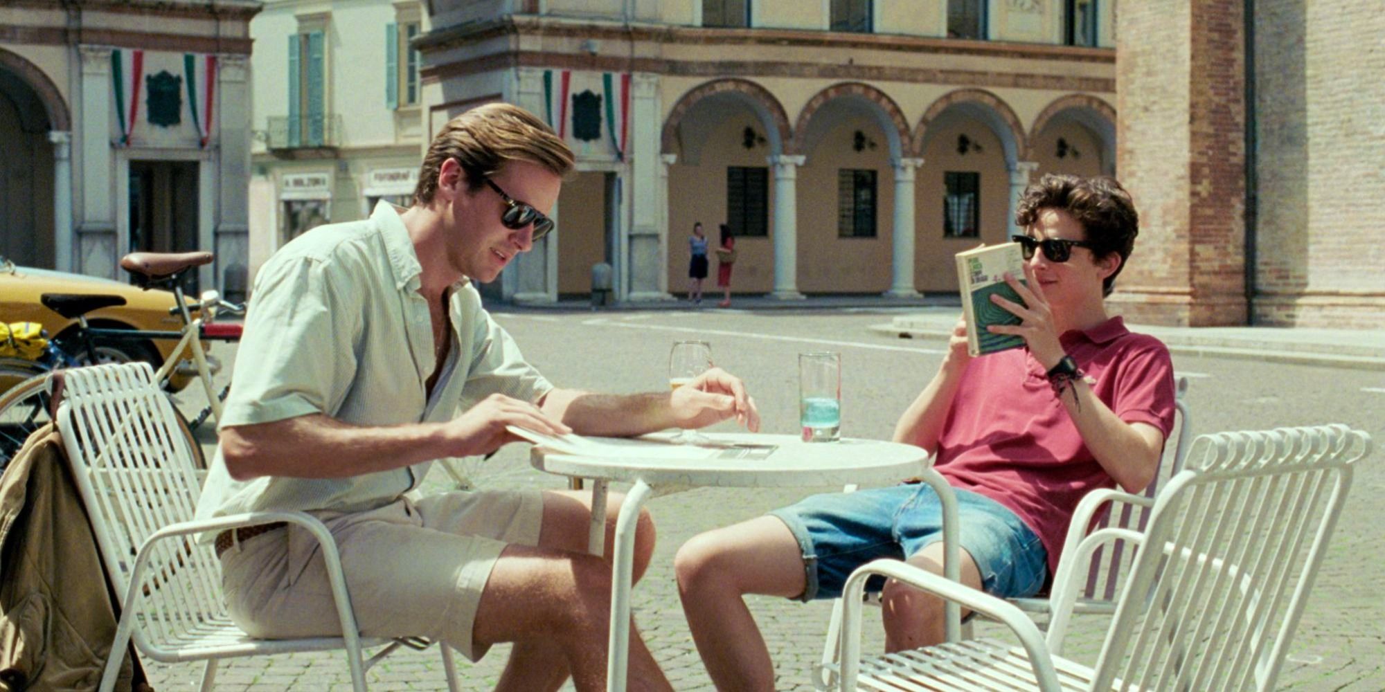 Armie Hammer and Timothée Chalamet as Oliver and Elio reading while sitting on a table in Call Me By Your Name