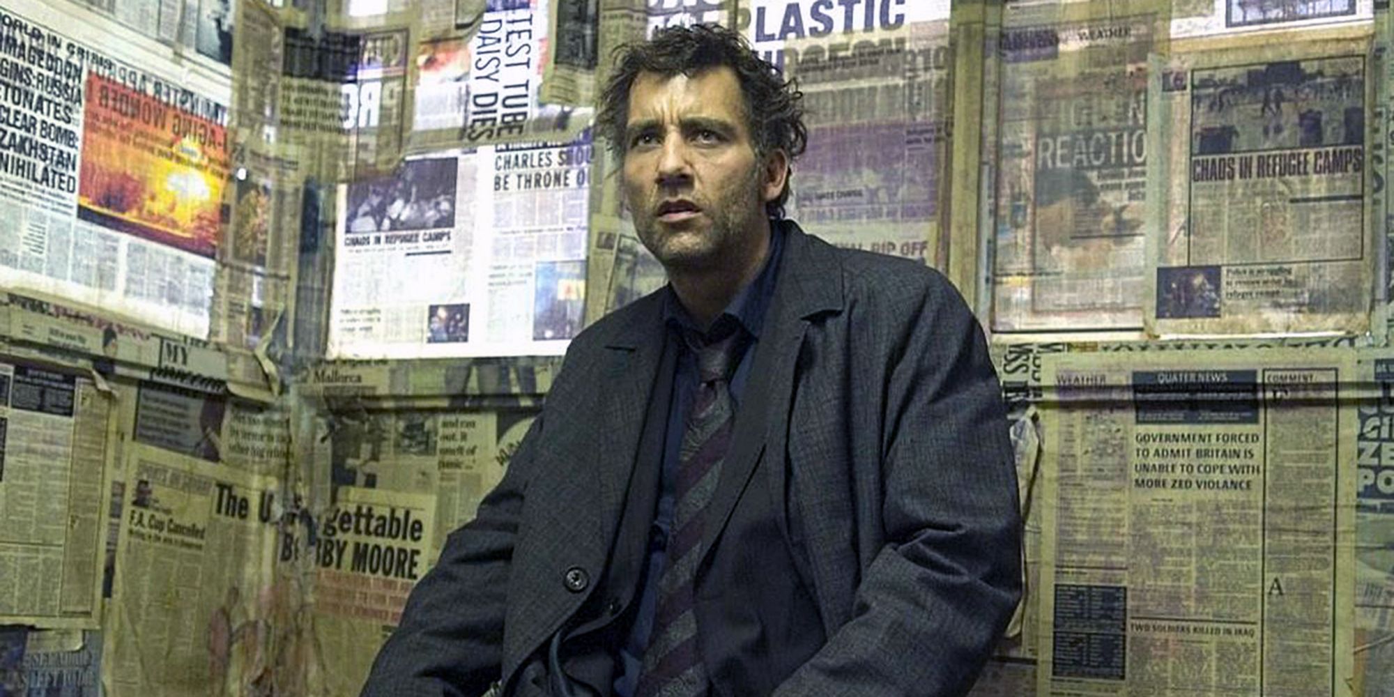 Clive Owen assis et l'air inquiet dans Children of Men.