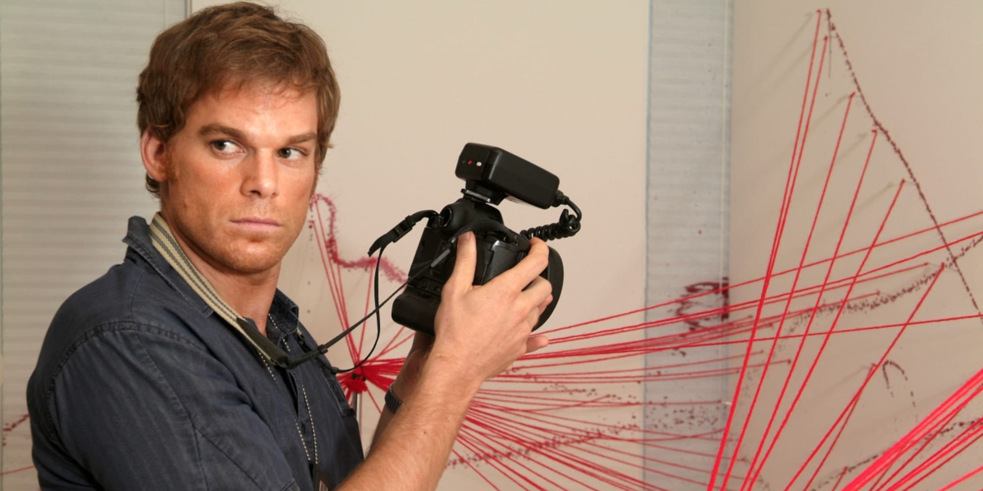 Michael C. Hall prend des photos d'une scène de crime dans Dexter.