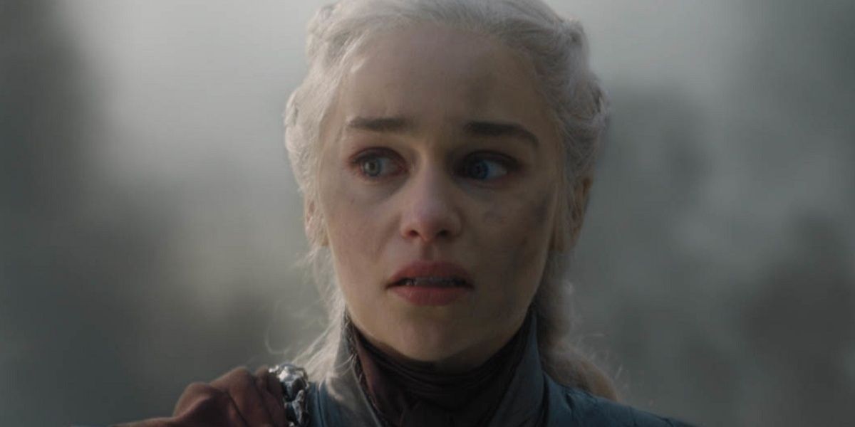 Emilia Clarke as Daenerys Targaryen looks distraught surrounded by gusts of dirt and smoke.
