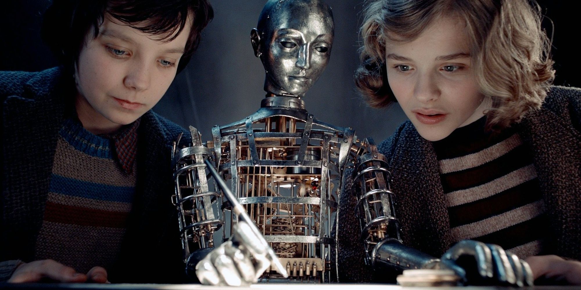 Asa Butterfield & Chloë Grace Moretz regardant un robot dans Hugo