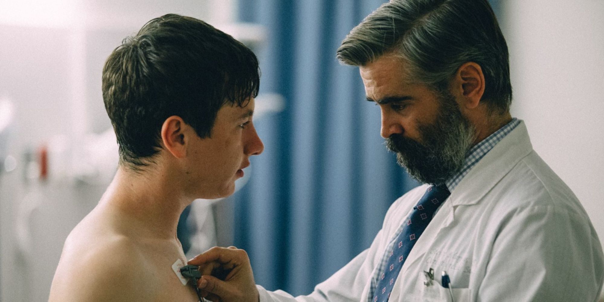 Steven (Colin Farrell) applying electrodes to Martin's (Barry Keoghan) chest in The Killing of a Sacred Deer