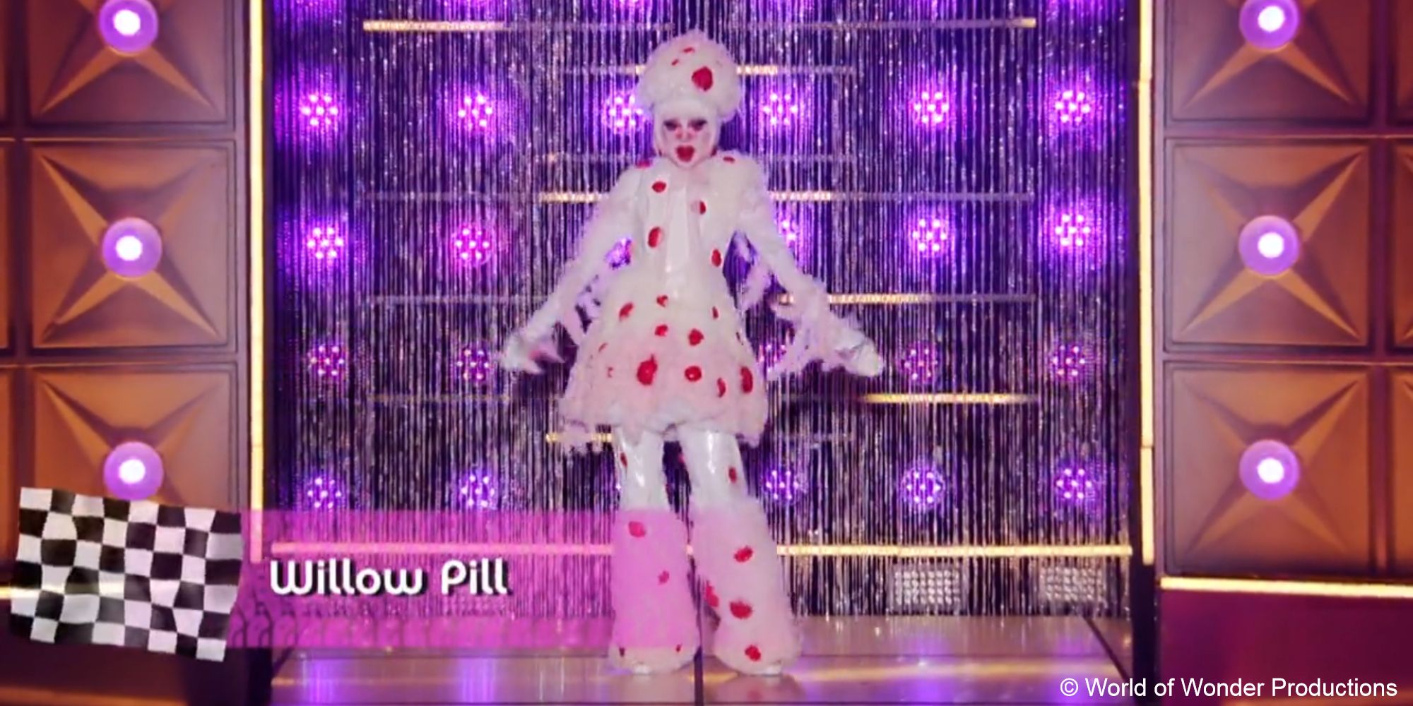 A still of drag queen Willow Pill wearing a red and white bleeding tooth fungus-inspired outfit