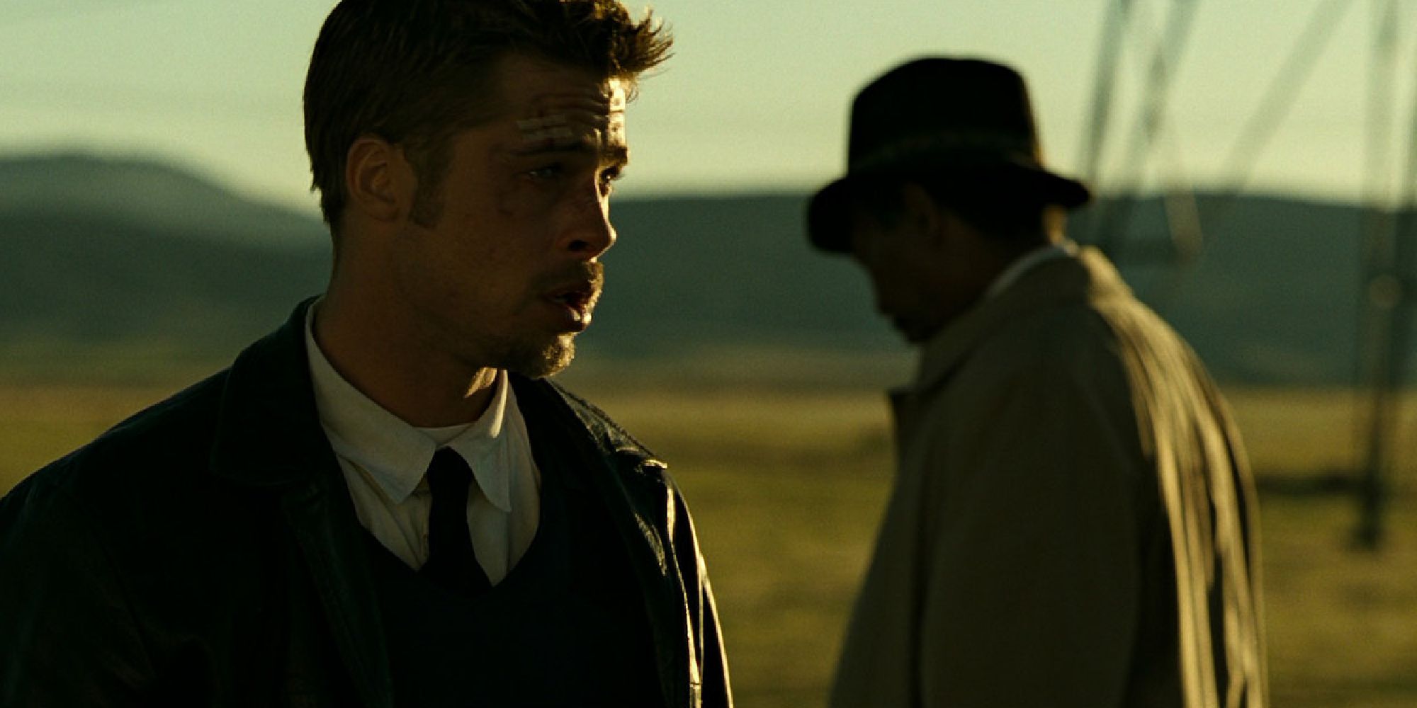 Sergeant Mills (Brad Pitt) looks into the distance distraught as he stands in a large field at sunset.