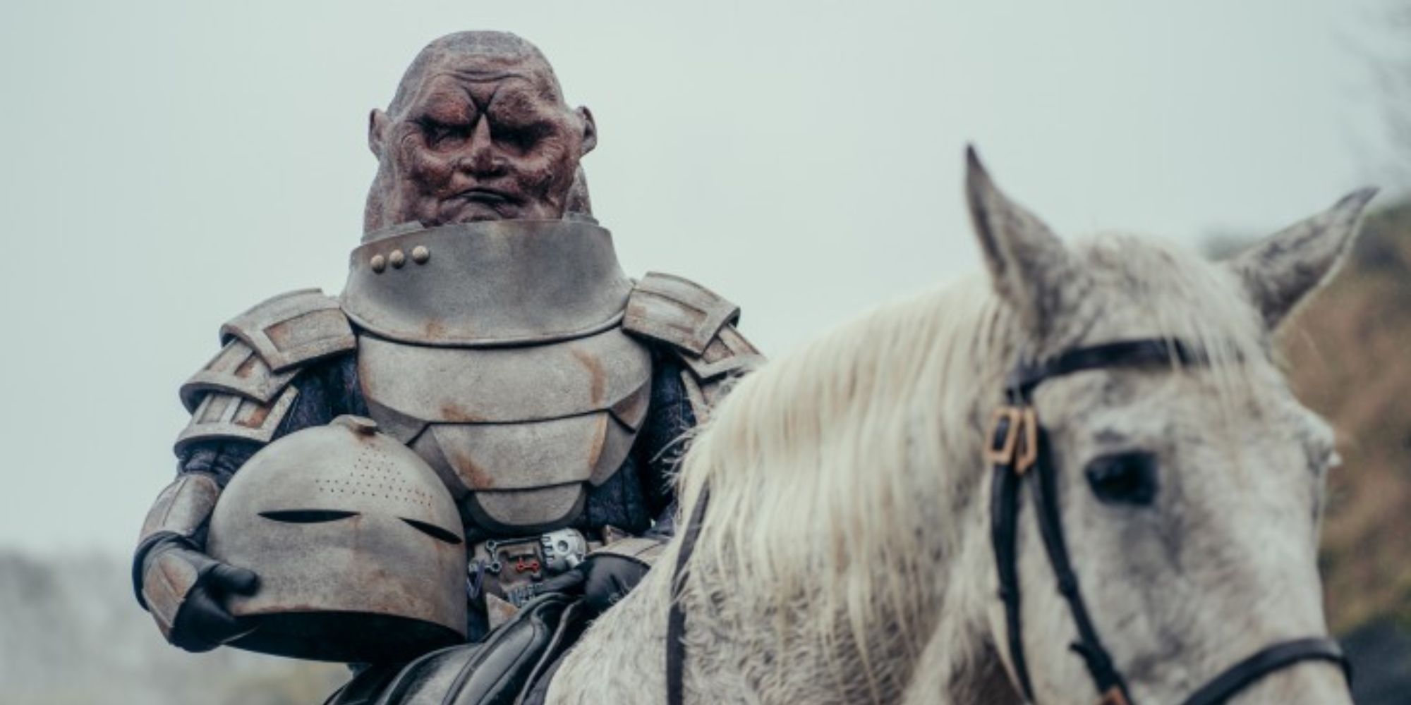 A Sontaran general with his helmet in one hand sits atop a horse