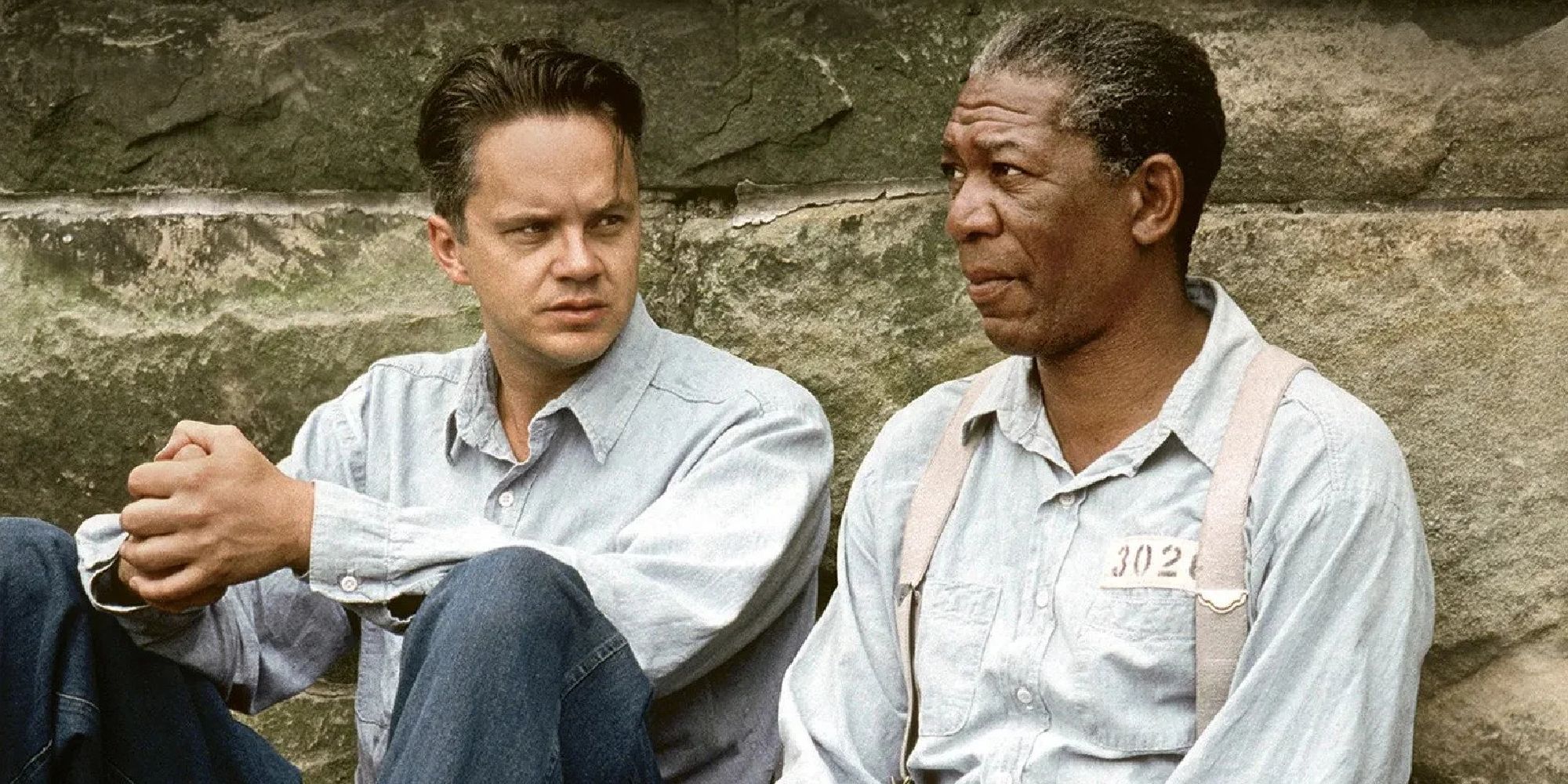 Andy Dufresne and Red Redding sitting next to each other talking in The Shawshank Redemption