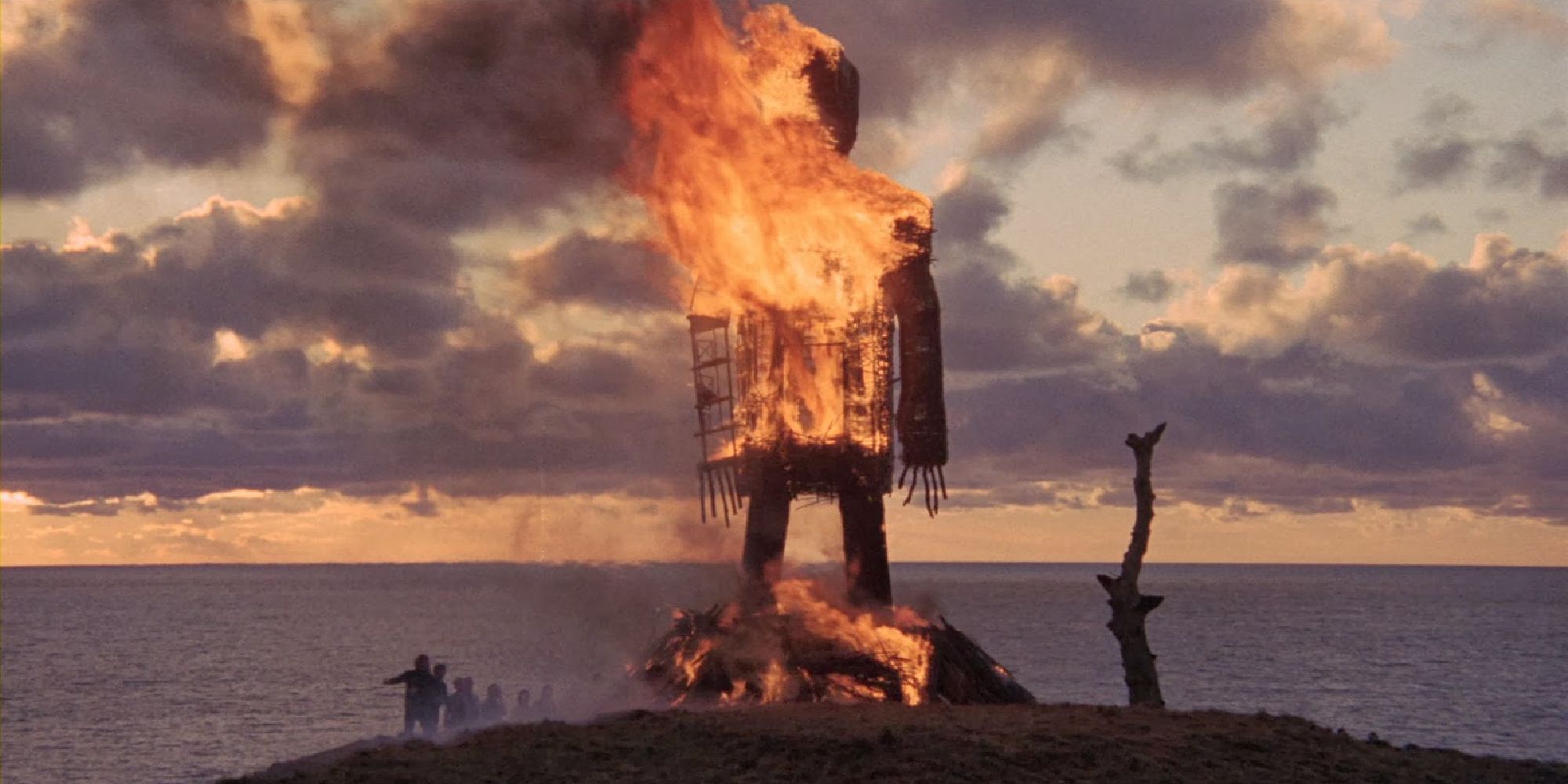 A giant wicker man burning underneath a sunset
