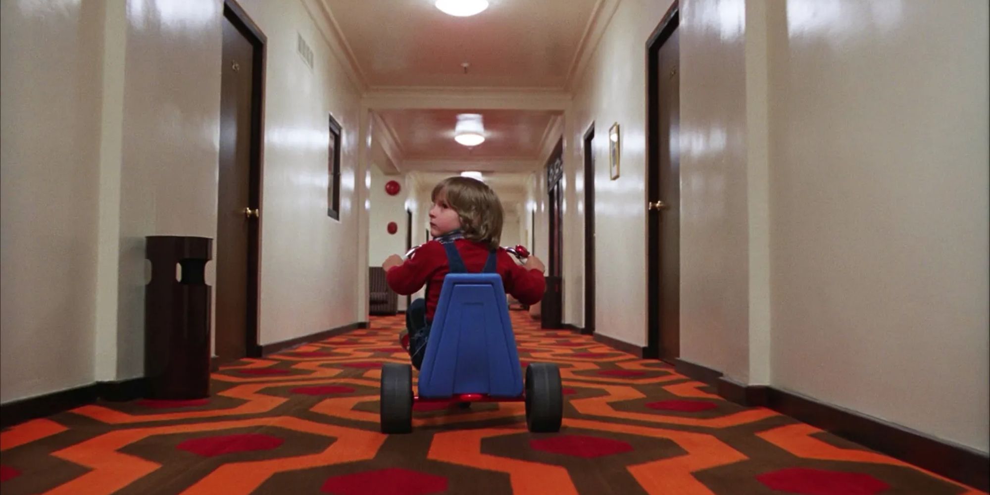 Danny Lloyd as Danny Torrance riding his bicycle in the Overlook Hotel in Stanley Kubrick's The Shining