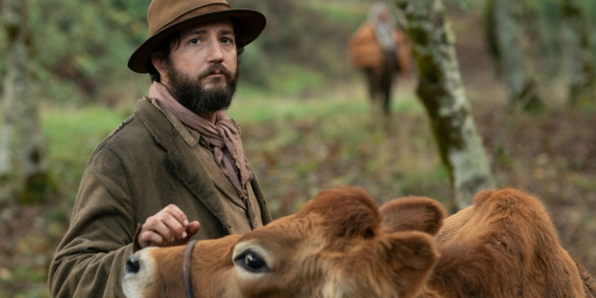 John Magaro as Cookie, petting a cow in First Cow