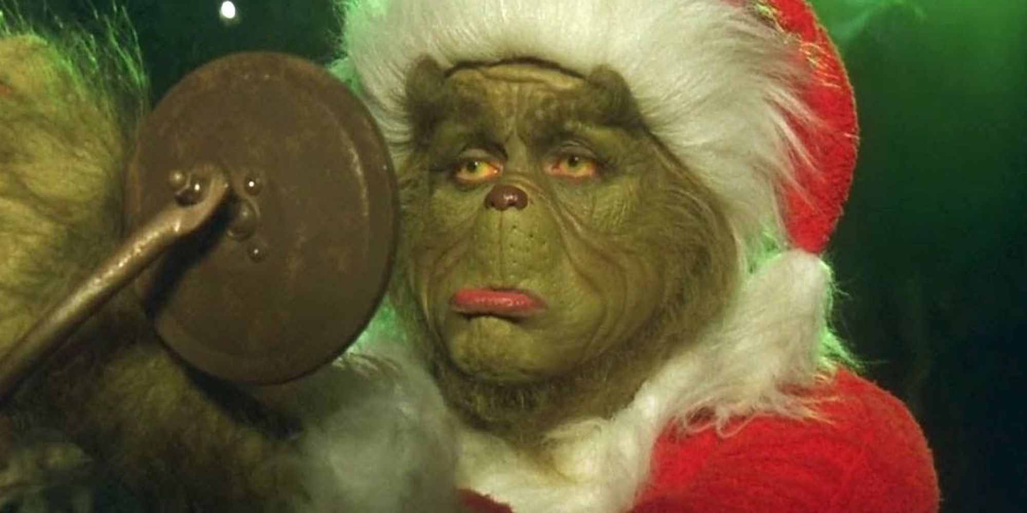 Jim Carrey as the Grinch pouting in a car side mirror dressed as Santa Claus in How the Grinch Stole Christmas