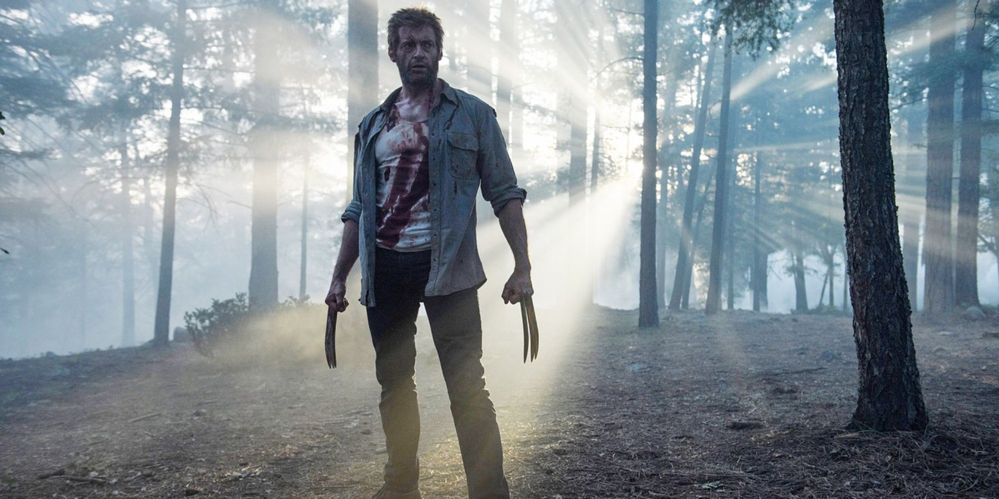 Logan with blood on his shirt standing on a forest in Logan