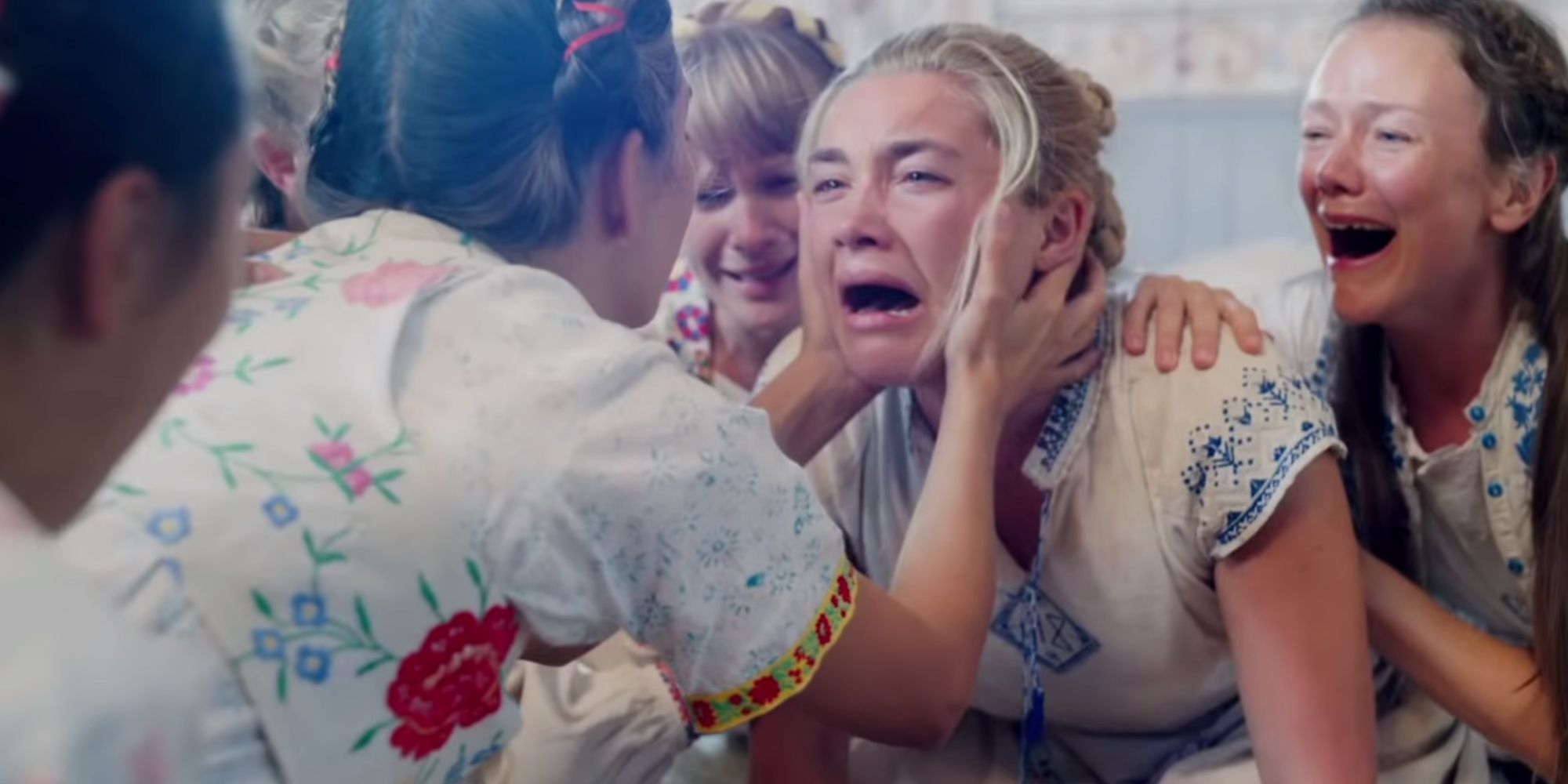 A woman is comforted by a group of women during a panic attack in Midsommar.