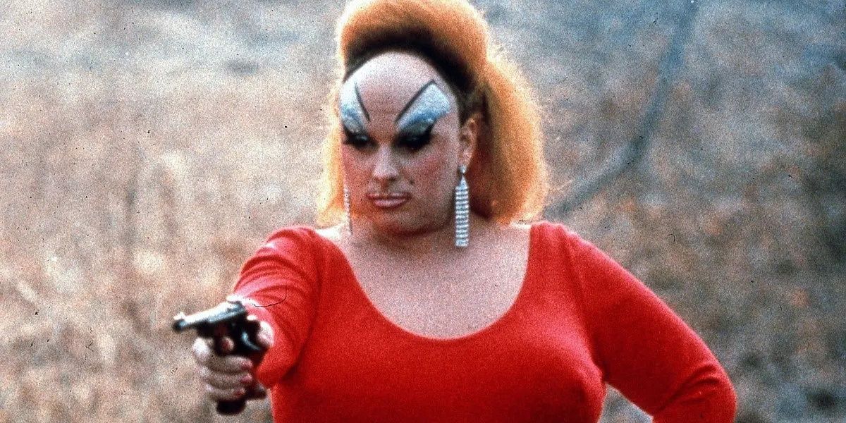 Divine aiming a gun at something off-camera in Pink Flamingos.