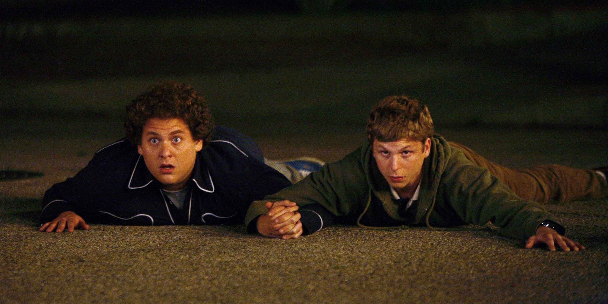 Jonah Hill and Michael Cera holding hands on the ground in Superbad