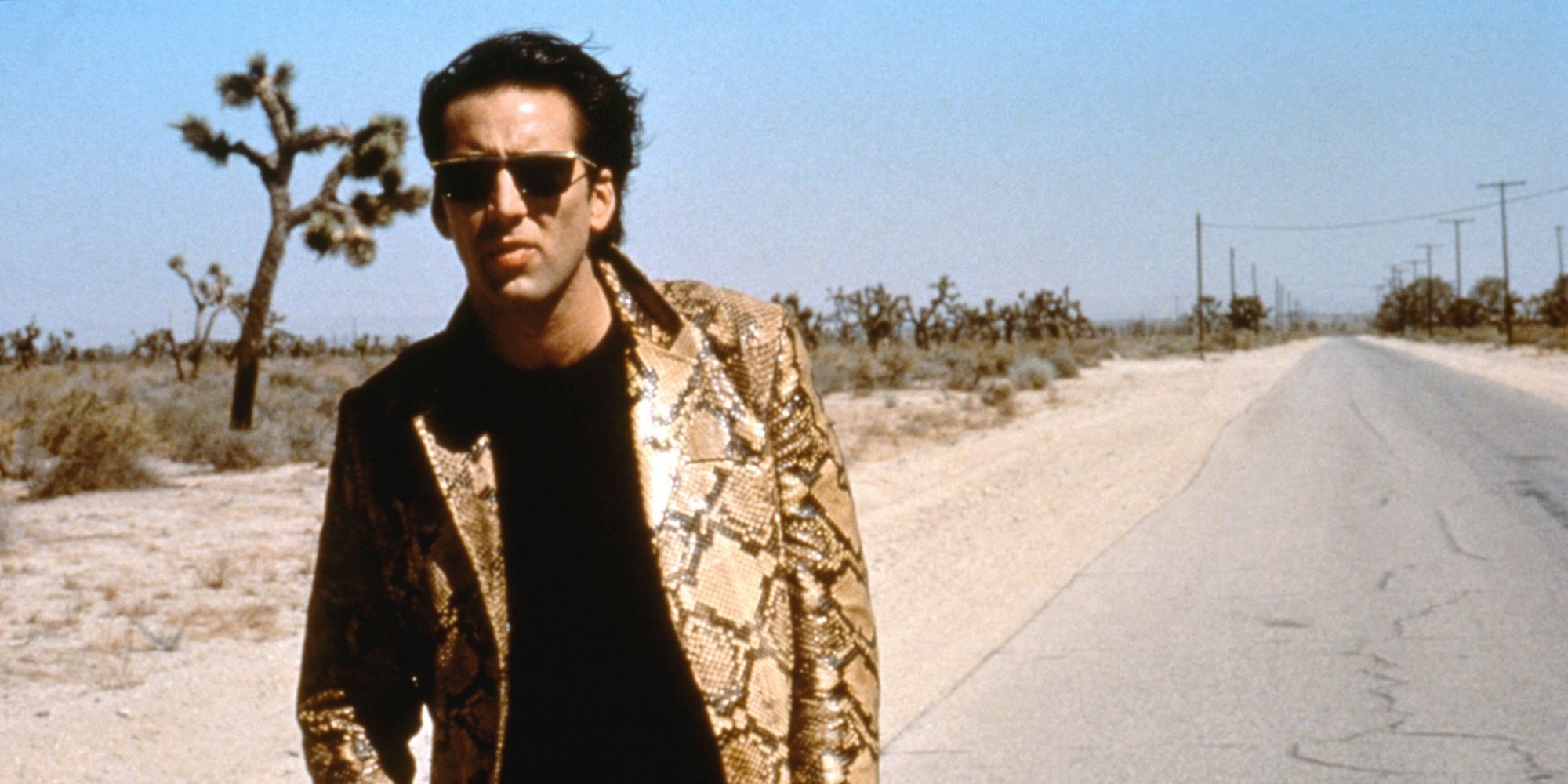 Nicolas Cage walking on the road in a snake skin jacket in Wild At Heart