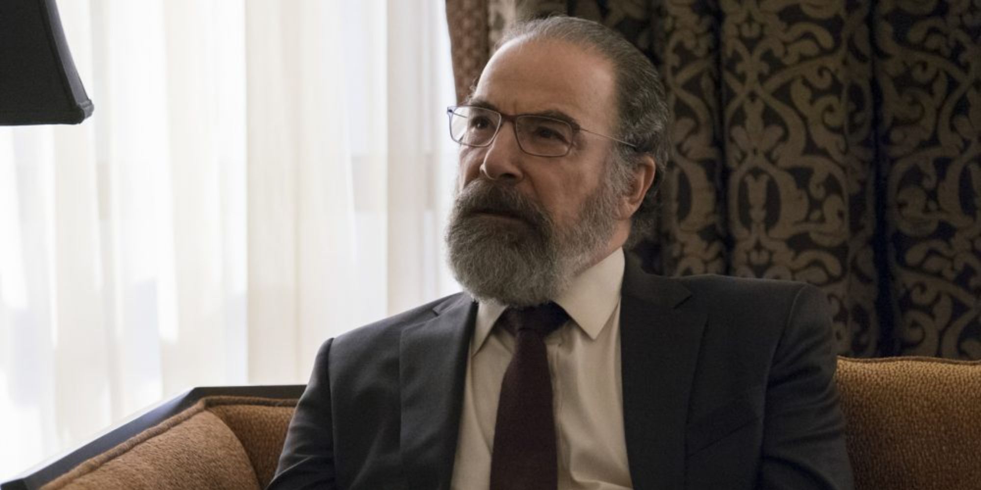 A man in suit and glasses sit on the sofa