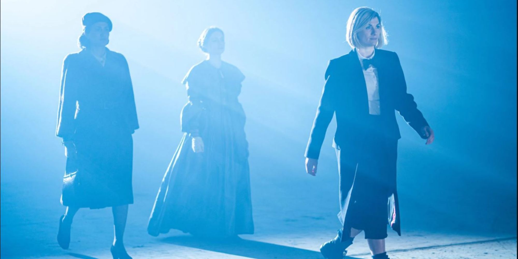 The 13th Doctor strides to the right, bathed in light, followed by Ada Lovelace and Noor Inayat Khan