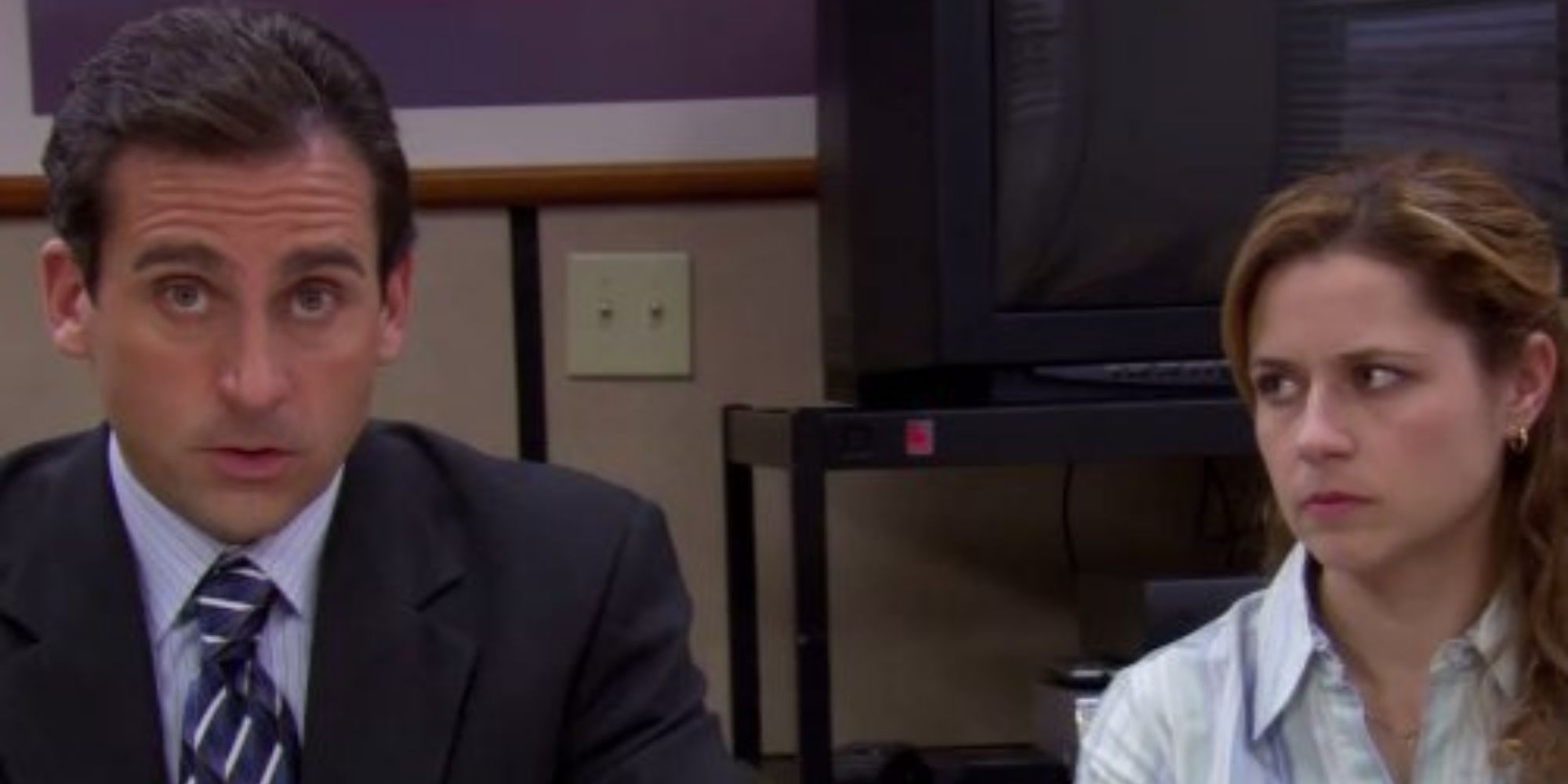 Michael talks to the camera while Pam stares skeptically at him