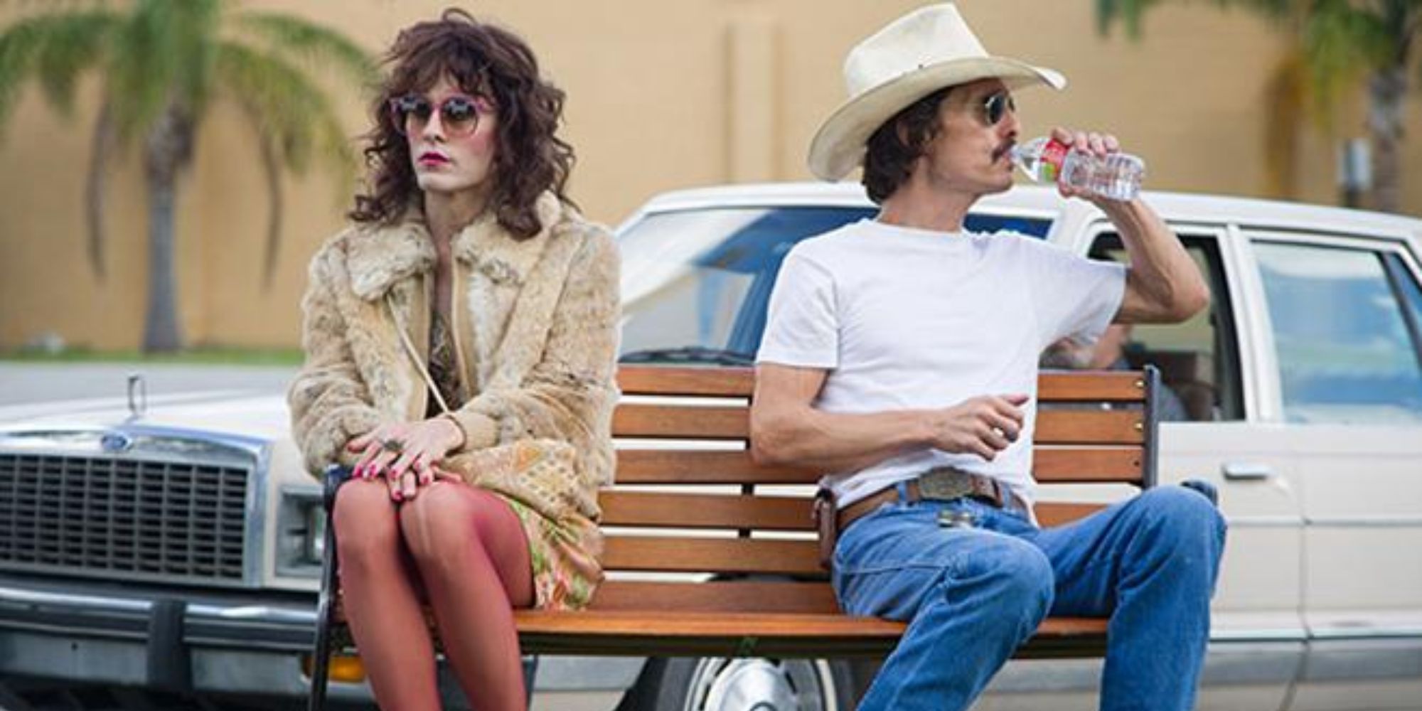 A woman and a man sitting on a bench but facing different directions