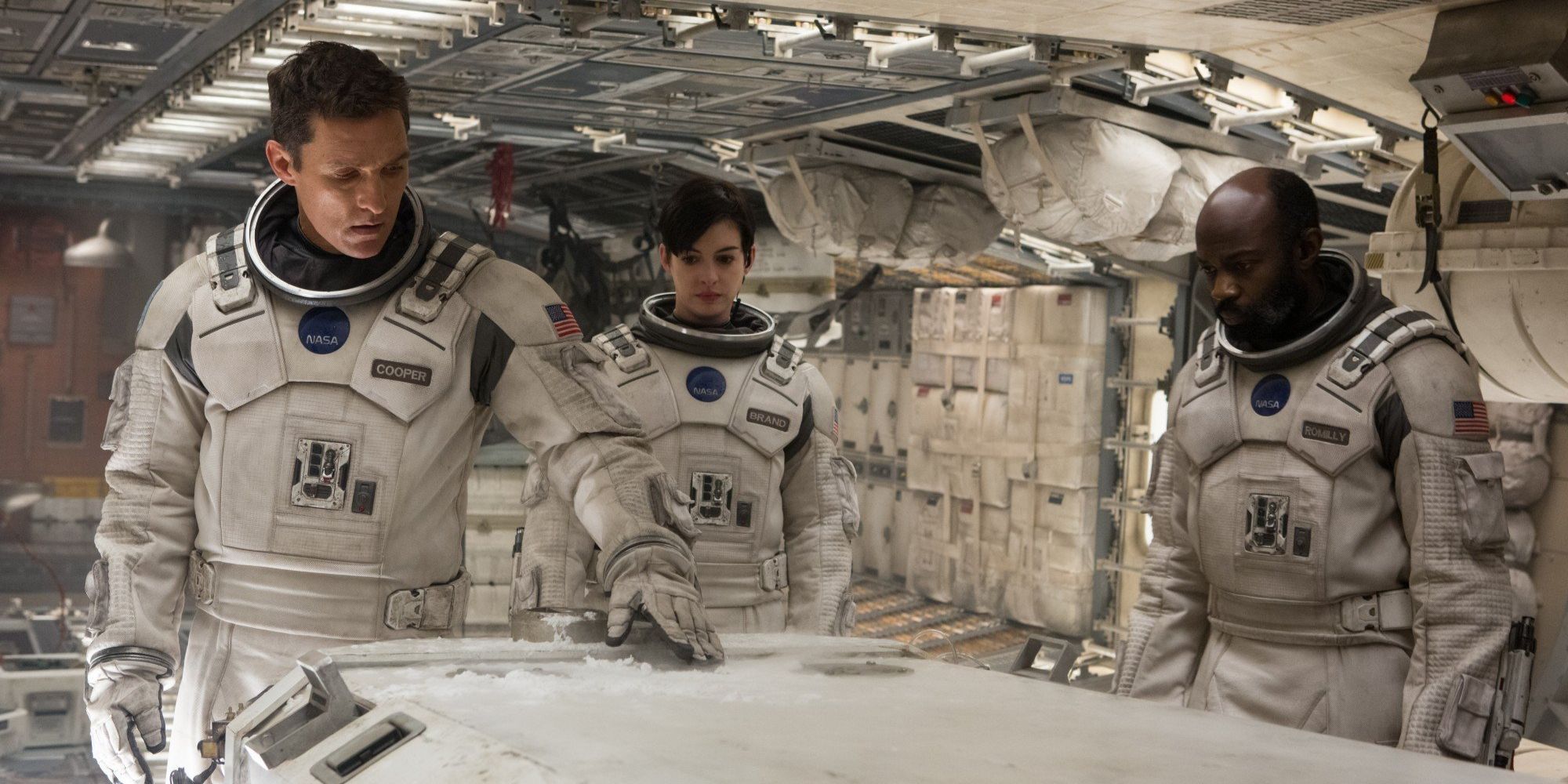 Coop (Matthew McConaughey), Professor Romilly (David Gyasi), and Dr. Brand (Anne Hathaway) looking at a cryostasis pod in Interstellar