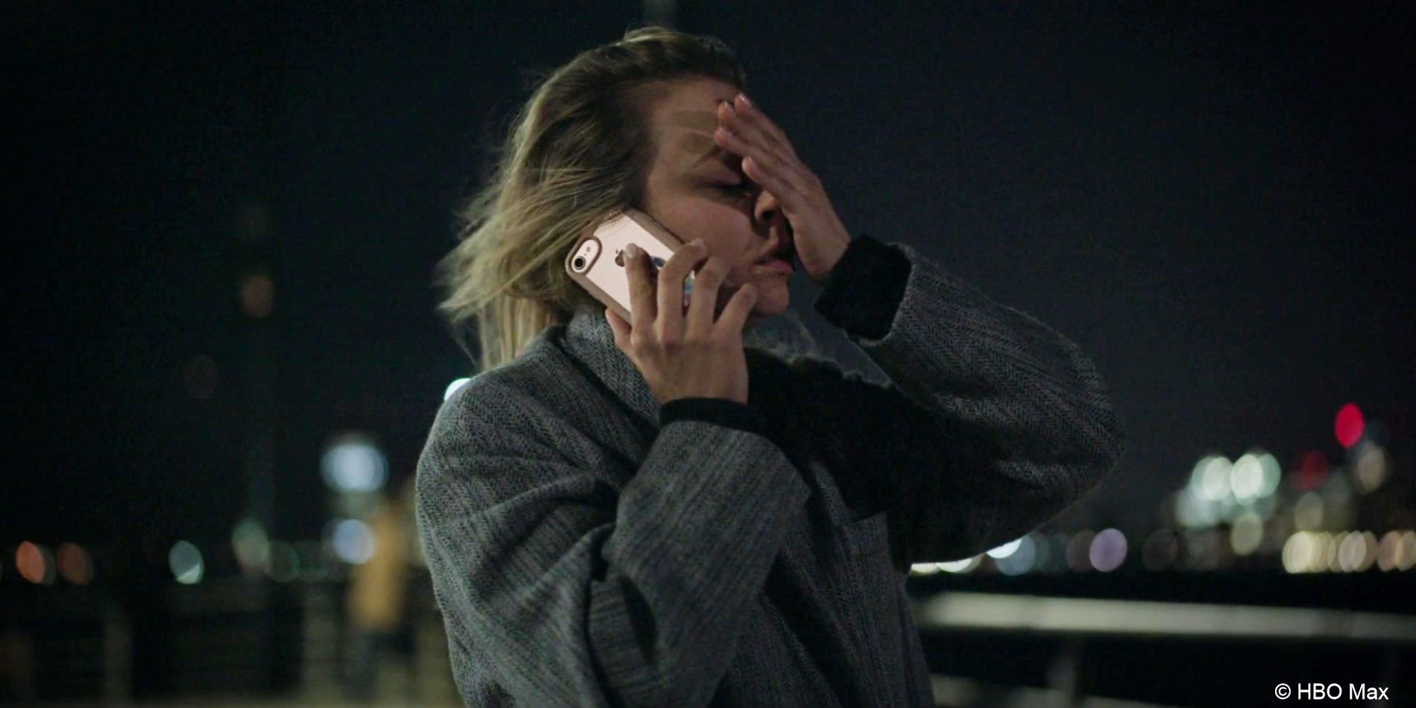 Cassie stands at the end of a pier at night talking on the phone, a hand held against her face