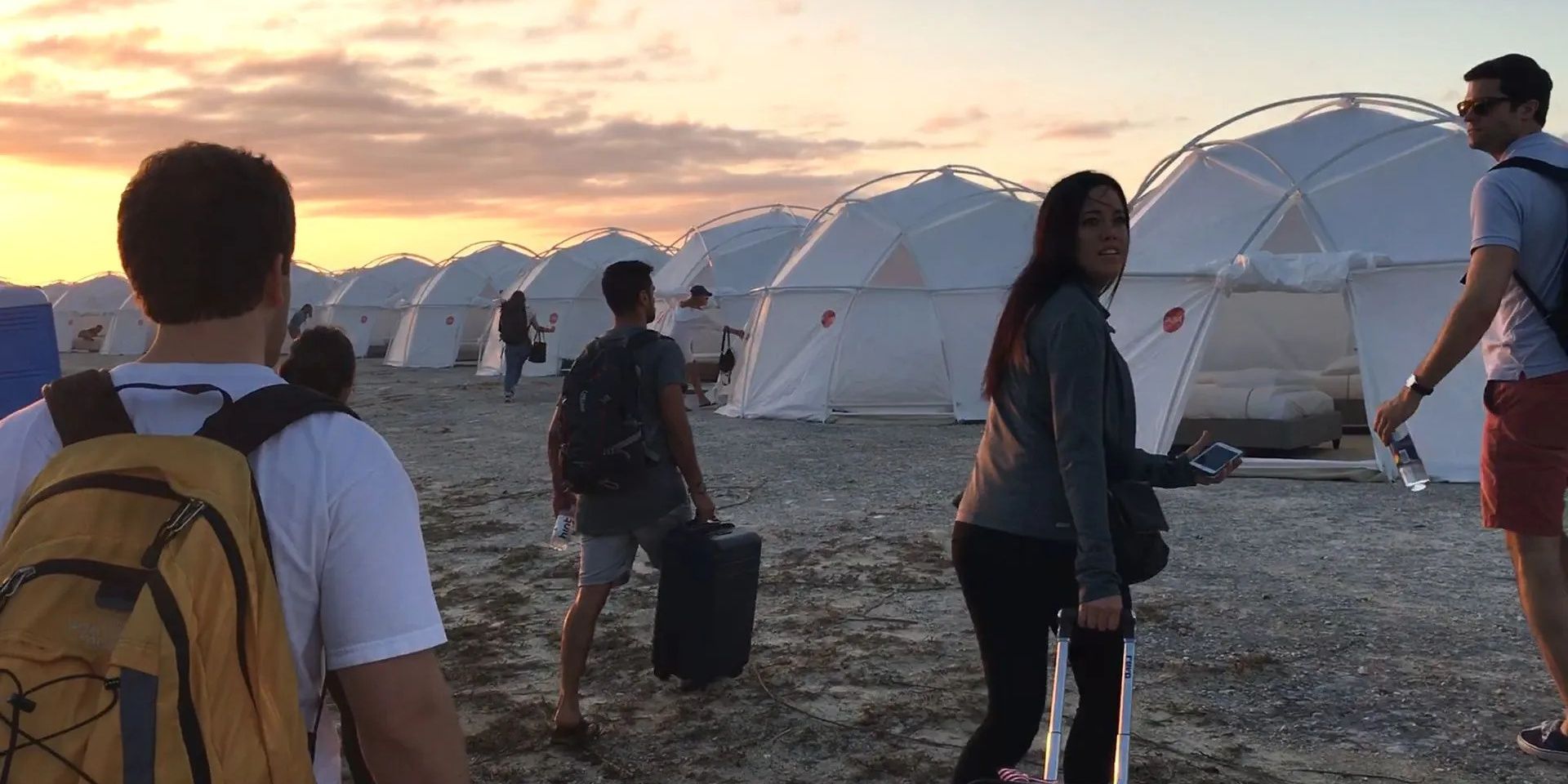 Fyre: The Greatest Party that Never happened, people walking towards UN tent, grey beach