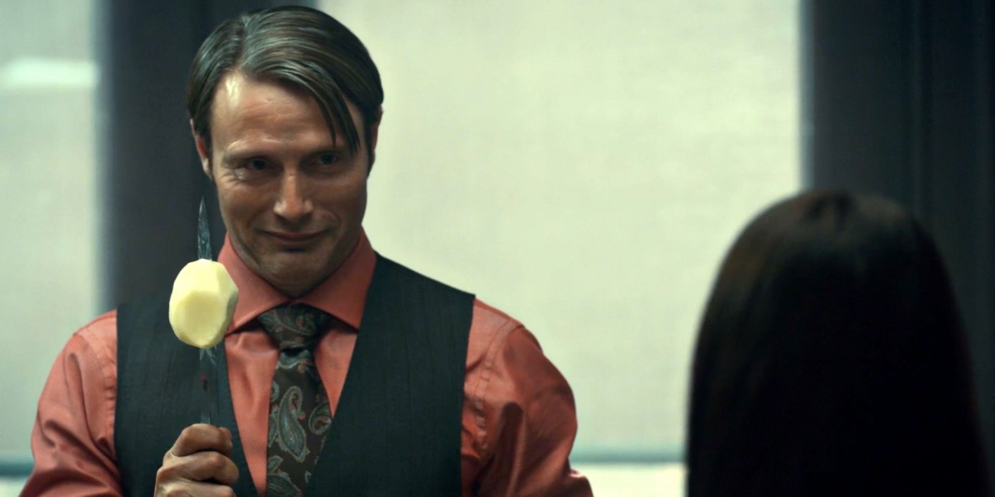 Mads Mikkelsen interpreta a Hannibal Lecter en Hannibal, sosteniendo un cuchillo largo con una patata.