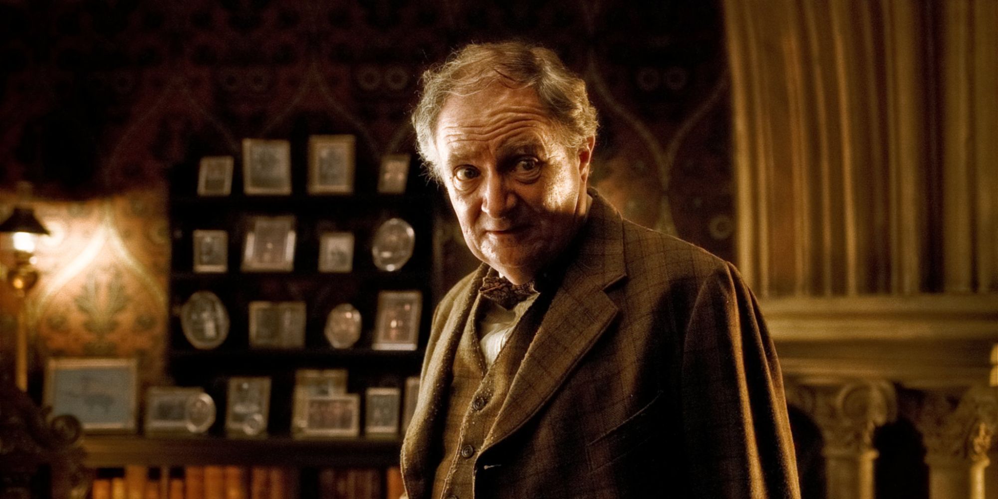 Slughorn played by Jim Broadbent in his office in front of a wall of photos in Harry Potter