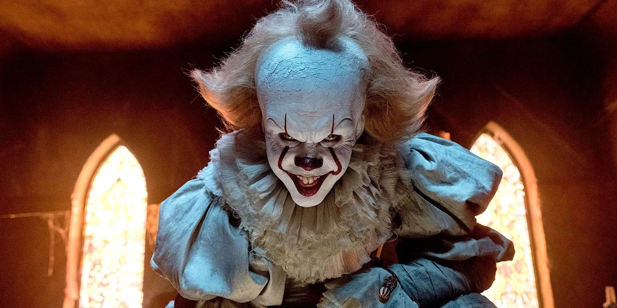 Bill Skarsgård as Pennywise the clown, looking at the camera and smiling nefariously in It