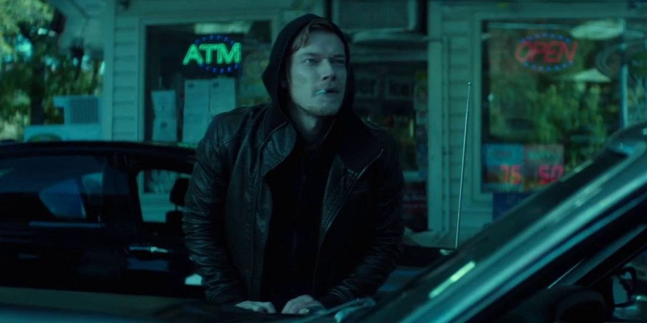 Alfie Allen as Iosef Tarasov smoking outside a gas station in John Wick