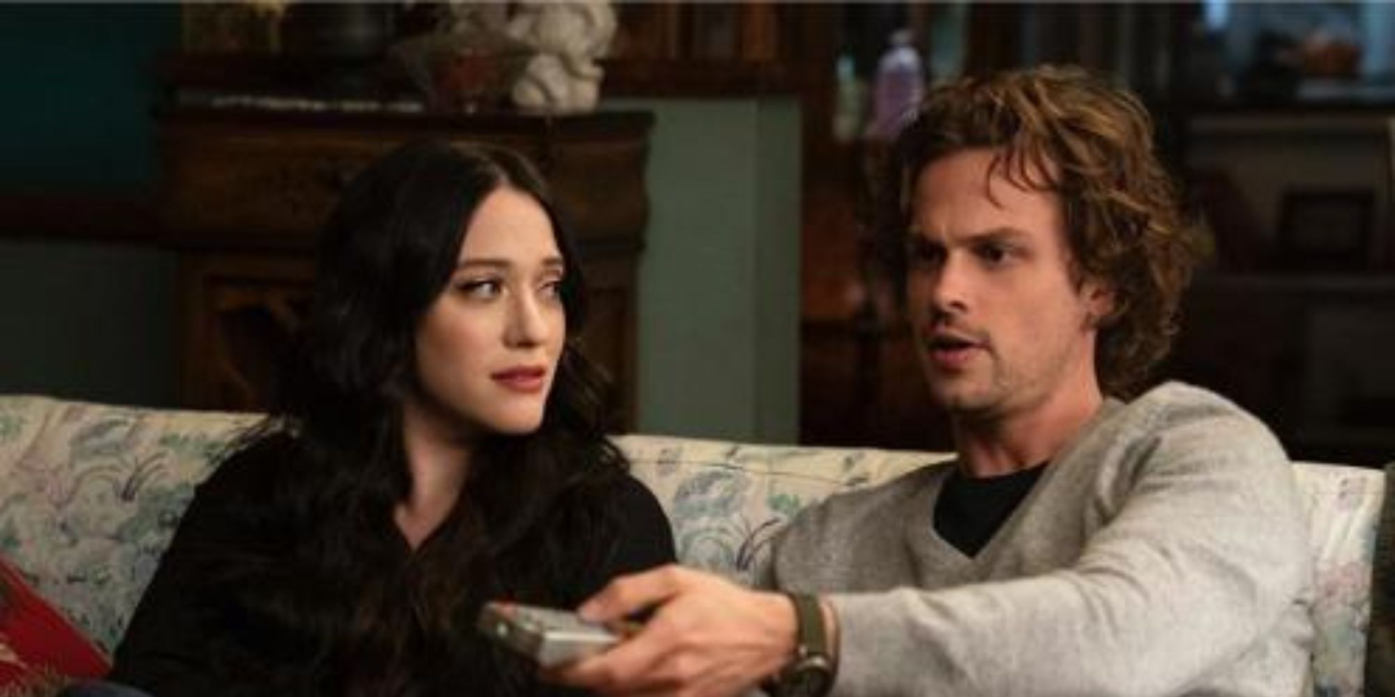 A man and a woman sitting on the couch, the woman is looking at the man while he is trying to change the channels