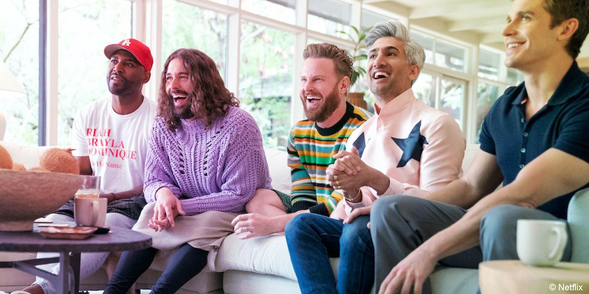 O elenco de Queer Eye Karamo, Jonathan, Bobby, Tan e Antoni estavam sentados sorrindo em um sofá